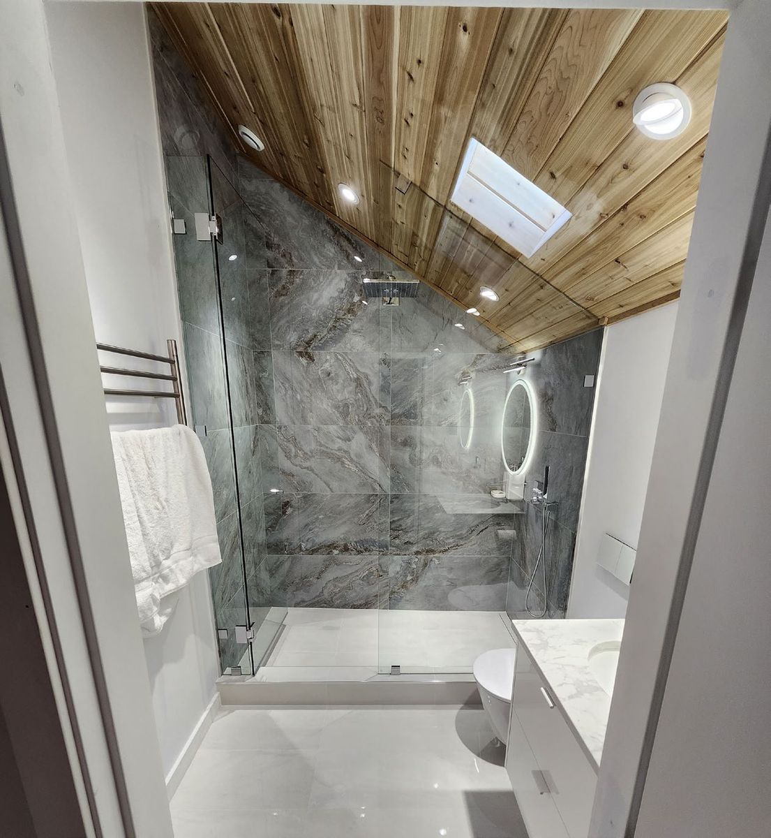 Attic bathroom after renovation with glass shower, stone walls and cedar ceiling